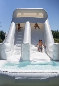 Marysville water slide rental with white bounce house and balloon garland