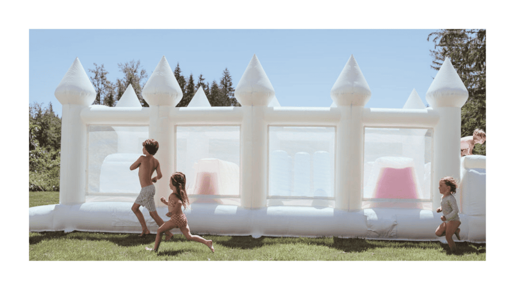 kids running and playing at a kids party in everett with a white luxury bounce house rental obstacle course.