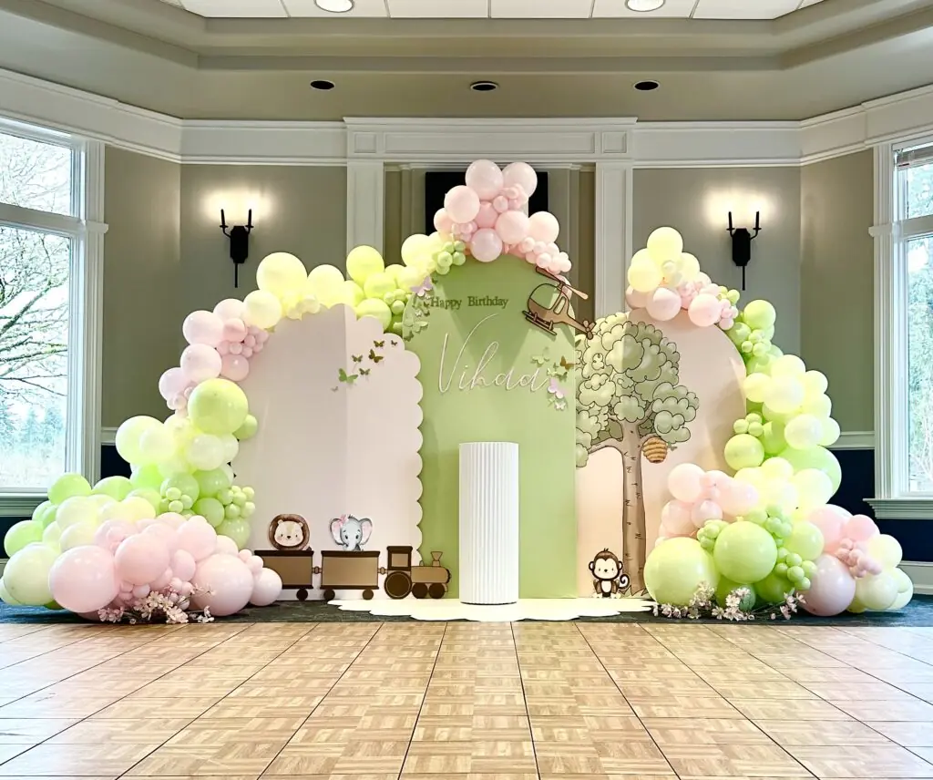 stunning backdrop setup for instagram photos for a 2nd birthday party in snohomish county & king county. Featuring a custom scalloped backdrop panel, winnie the pooh props, animal props, train props, large tree prop, custom cake stand, backdrop arch, scalloped floor mat, rainbow arch, custom vinyl signage, and balloon garlands from bradbury events.