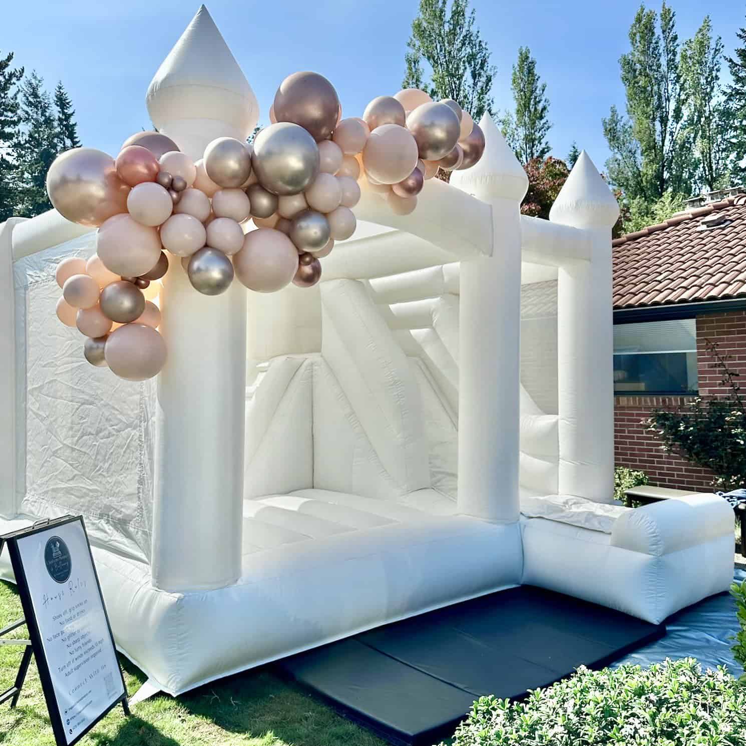 Ranier white bounce house rental in Everett with ivory, rose gold, and blush balloon garland for a 40th birthday.
