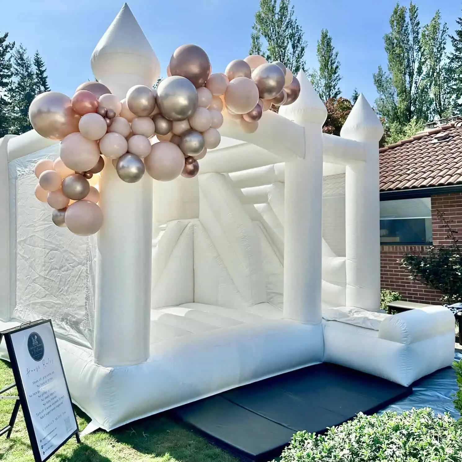 Ranier white bounce house rental in Everett with ivory, rose gold, and blush balloon garland for a 40th birthday.