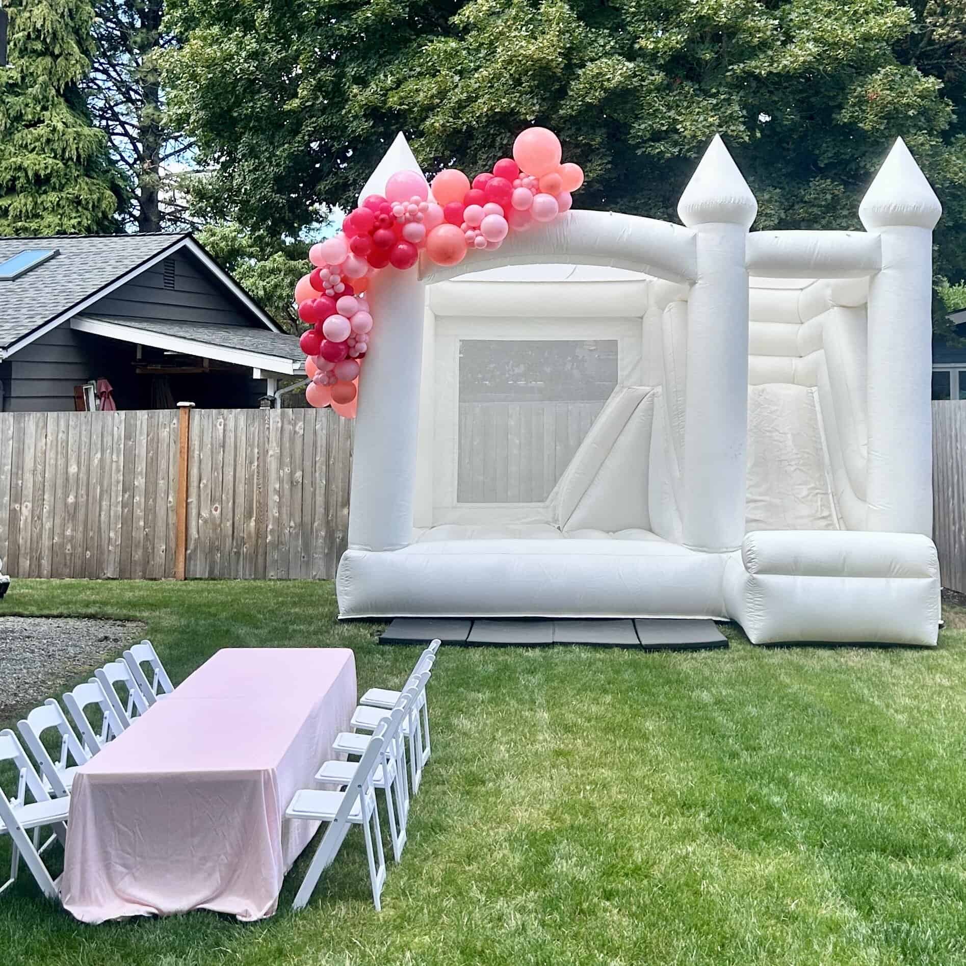 Ranier white bounce house rental in Bellevue, WA with blush, dusty rose, and peach balloon garland for a birthday party