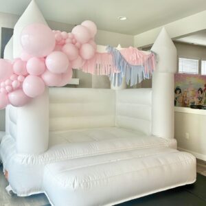 Indoor white bounce house rental with pastel pink balloon garland and fringe for princess-themed kids party in Everett and Bothell