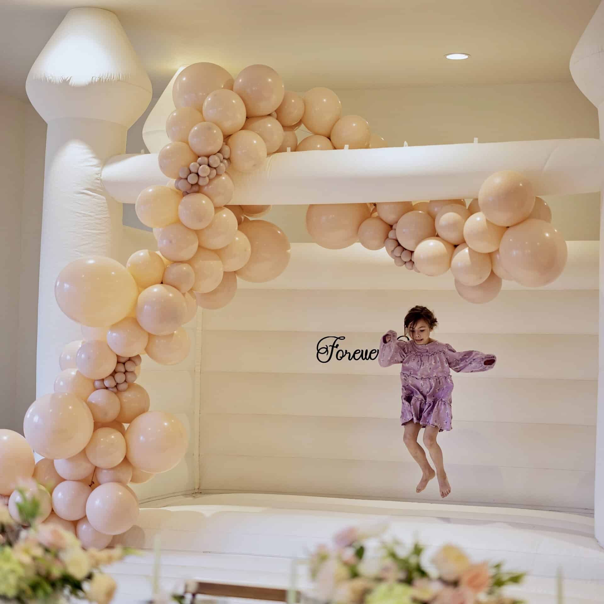 magnolia luxury bounce house rental, wedding bounce house, kids bouncing on white castle with balloons garlands. bounce in style with balloons. stylize your bouncer. luxury bounce house rental in snohomish & white bounce castle in snohomish