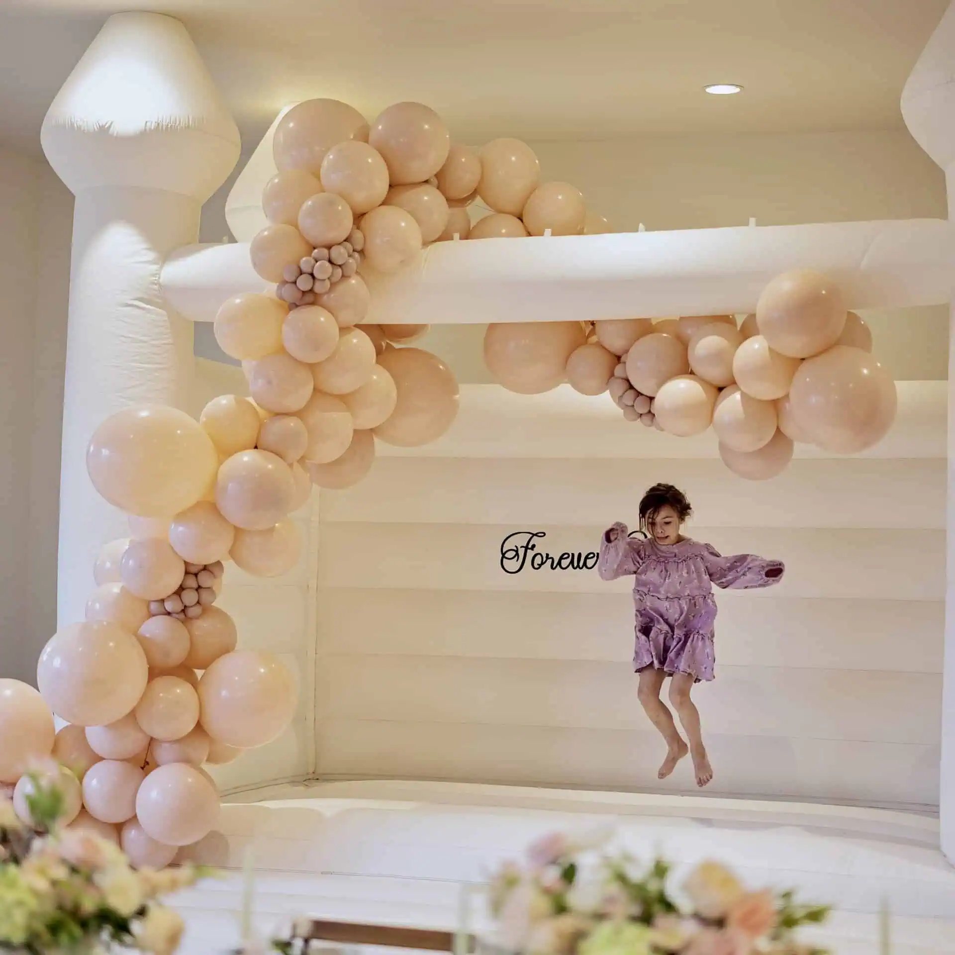 Luxury bounce house rental in Snohomish. White bounce castle with balloon garland & custom signage for Snohomish wedding.