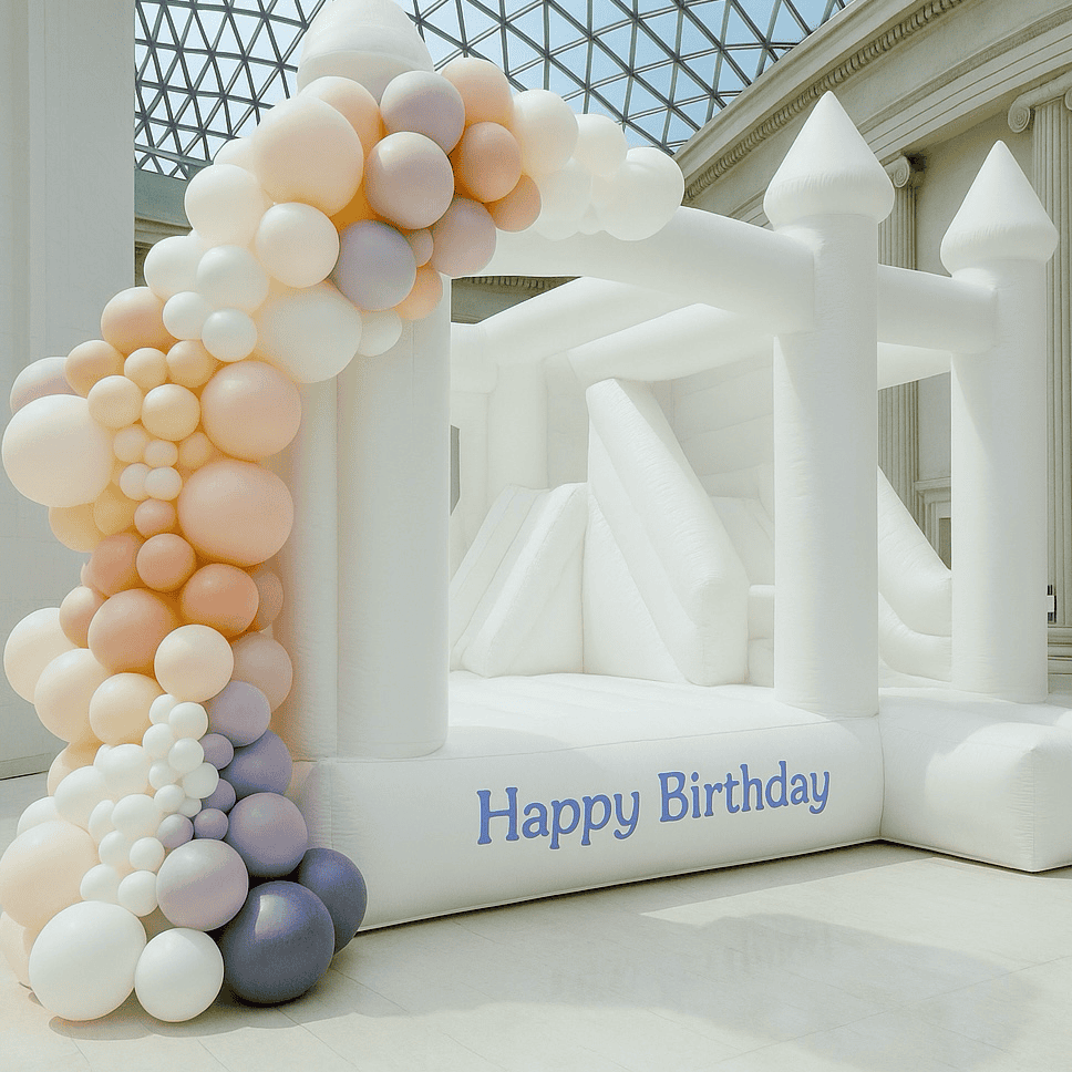Luxe Celebration Package hero-style image: white bounce house with large pastel balloon garland; Happy Birthday visible; editorial look.