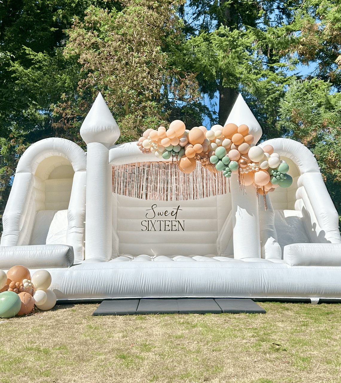 White Bounce Castle with balloon styling, vinyl signage and fringe decor for sweet 16 birthday party in snohomish county and king county