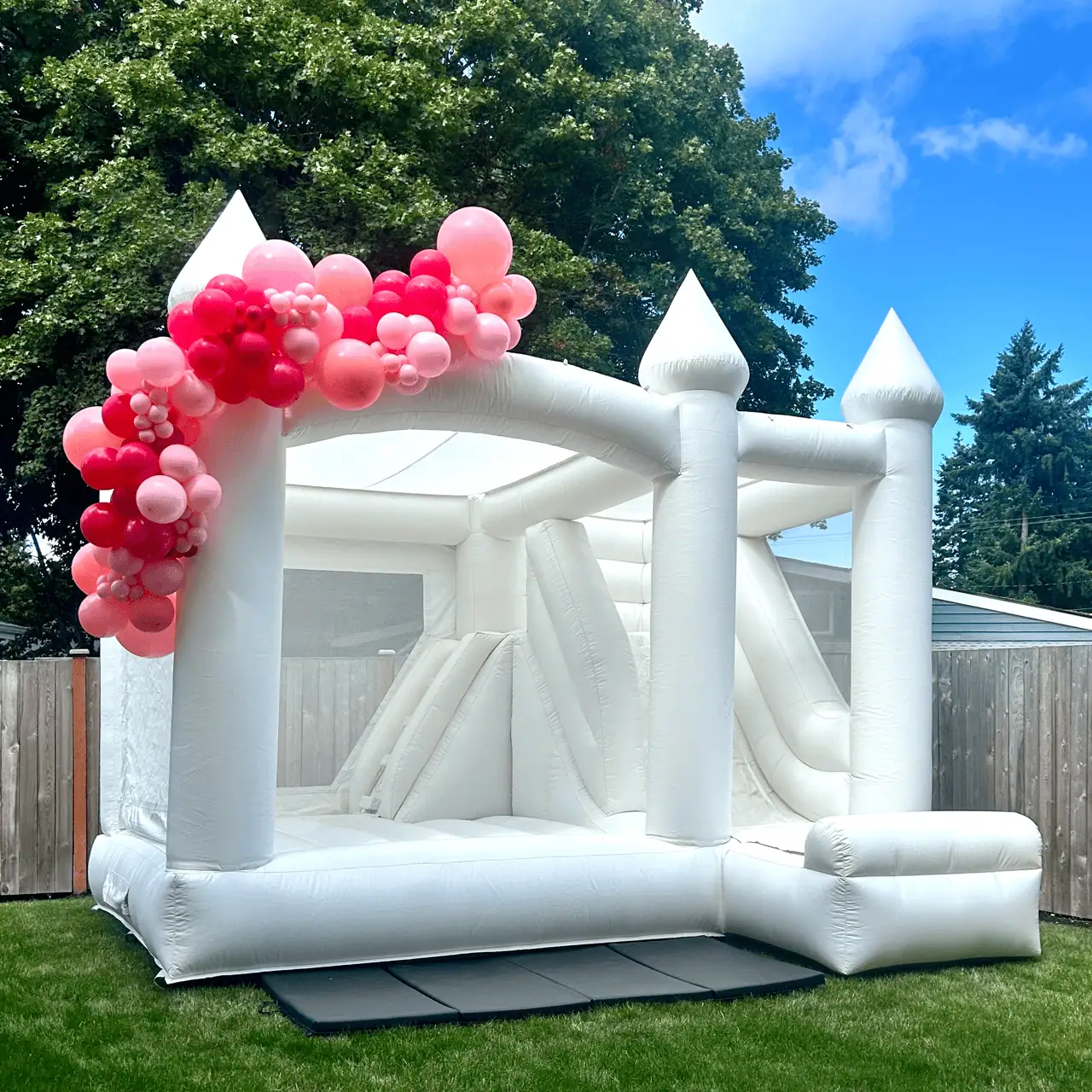 Rainier white bounce castle with a red and pink balloon garland at a birthday party in Bellevue