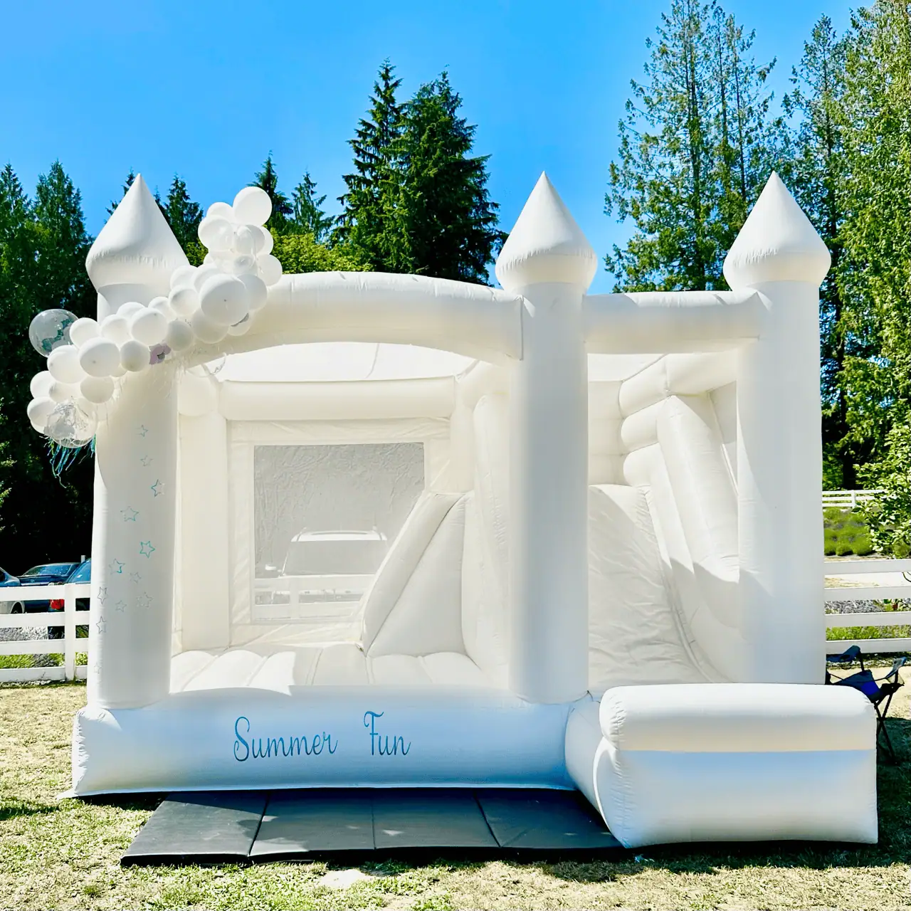 Rainier white bounce castle with a white balloon garland and a Summer Fun sign at a lavender farm in Arlington