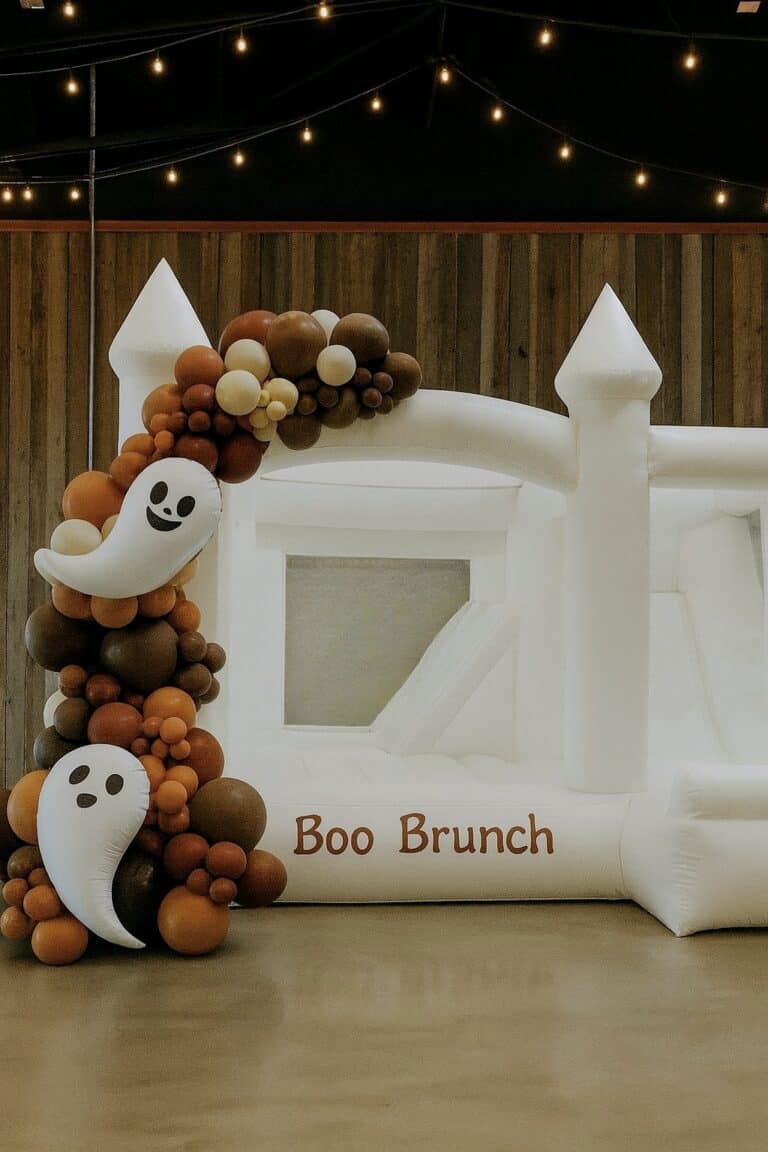White bounce house decorated with brown and Orange ghost balloon garland at a Halloween party in Lynnwood.