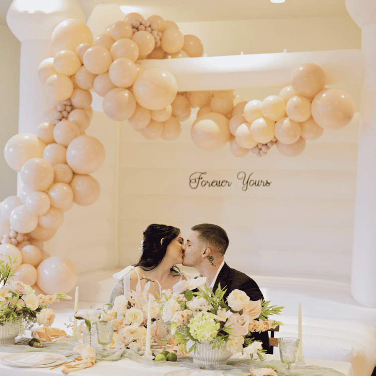 luxury white bounce houses for weddings - wedding bounce house for bridal showers styled with balloon garland and vinyl signage