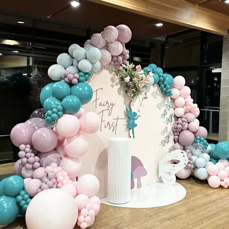 Outdoor bridal-style setup with pink balloon decor and a white bounce house; vertical BRIDE panel and styled props.