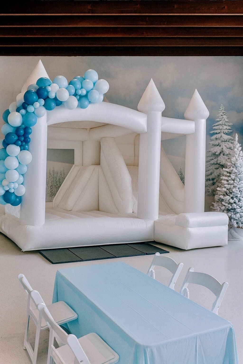 Photo: Winter Wonderland balloon decor with a luxury white bounce house rental styled for an indoor holiday event in Snohomish and King County.