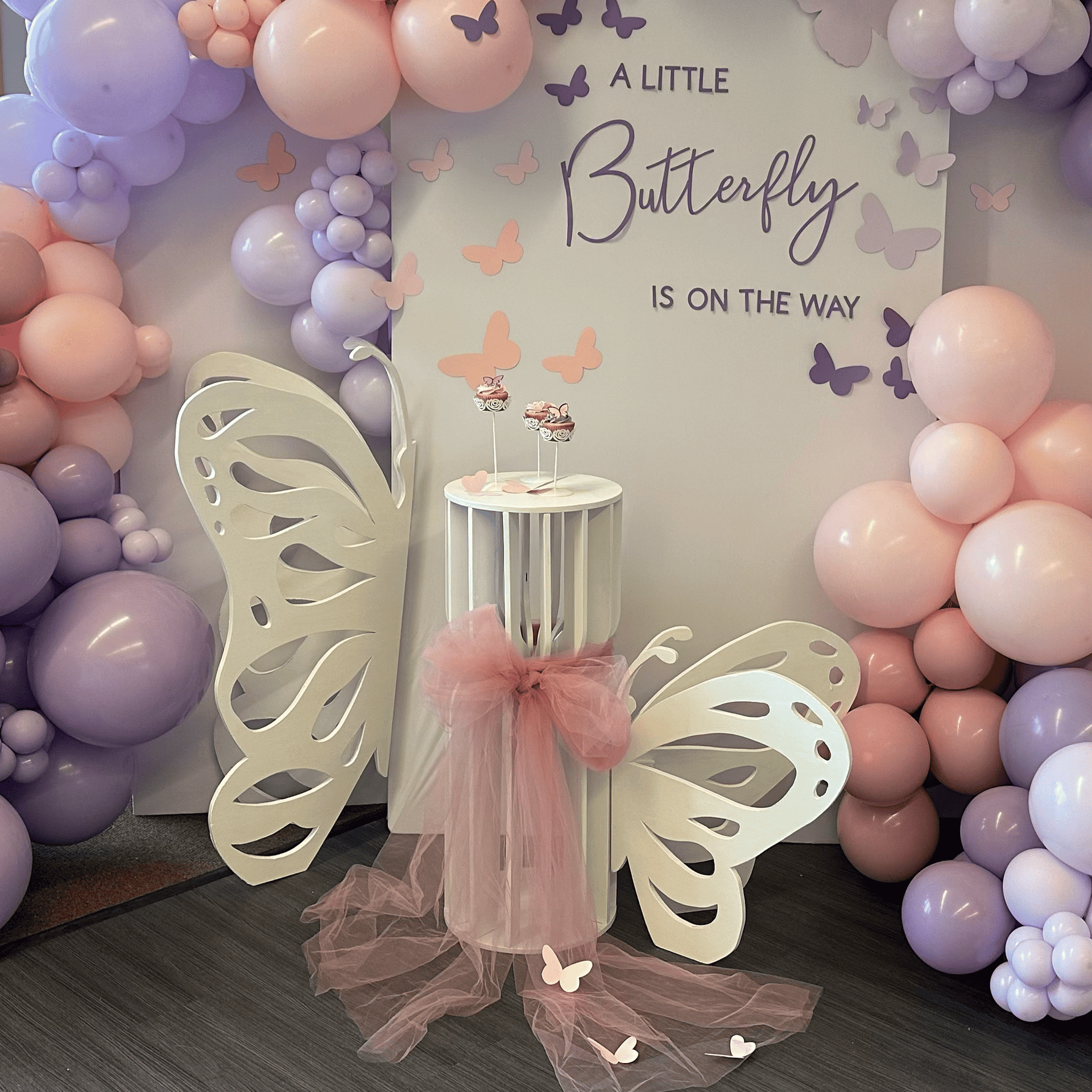 Photo: party props rental display with pedestals, Butterflies, balloon garlands, and backdrops for a baby shower at Rosehill Community Center