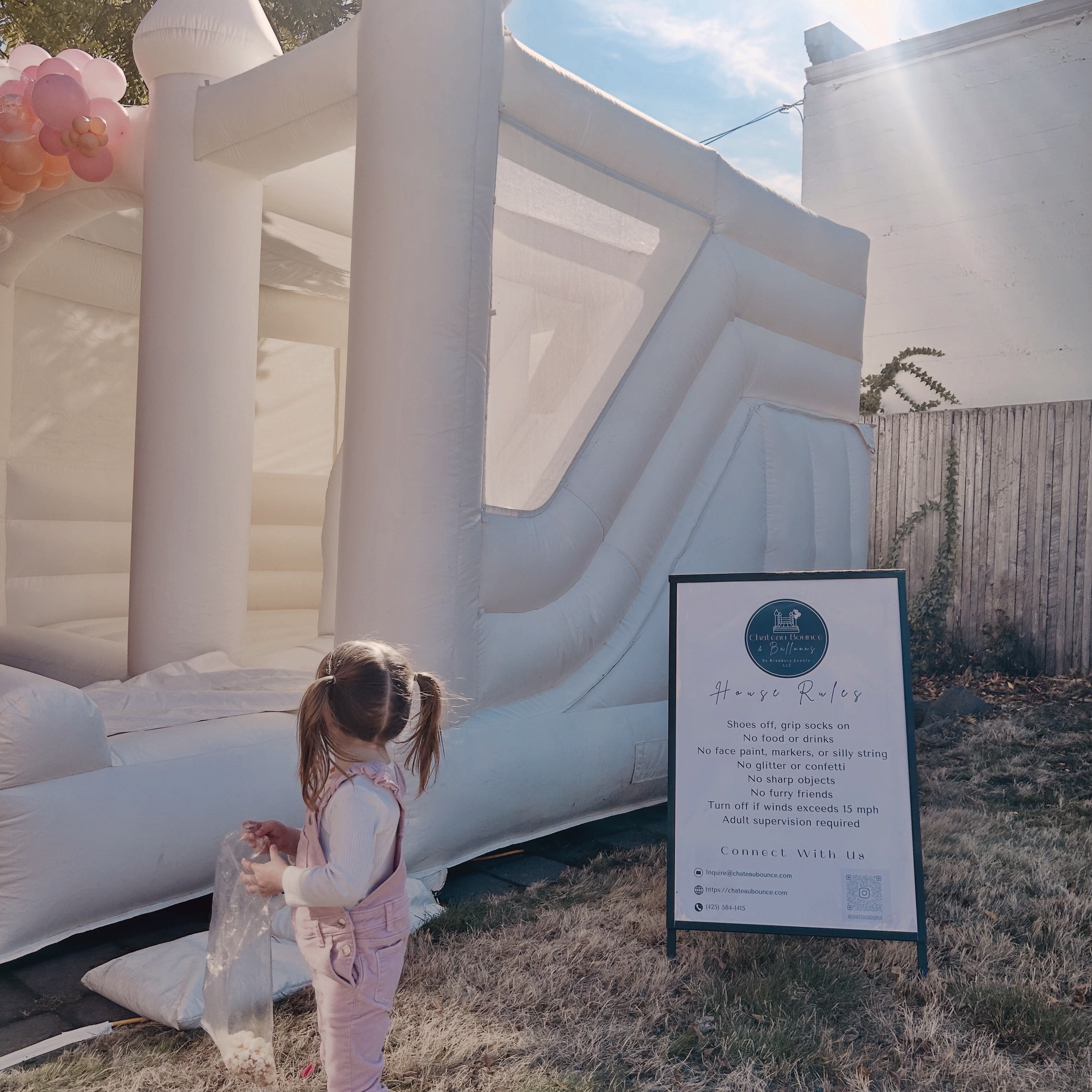 Ranier white bounce house with blush, peach, and white balloon garland for a birthday at Kenzthetics in Edmonds, WA