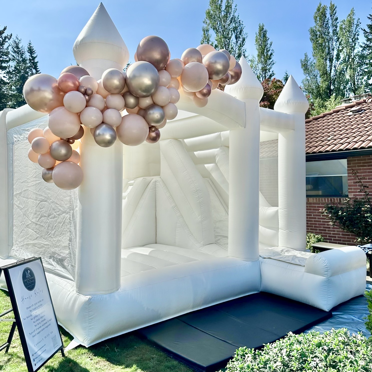 Ranier white bounce house with ivory, rose gold, and blush balloon garland for a 40th birthday in Everett, WA