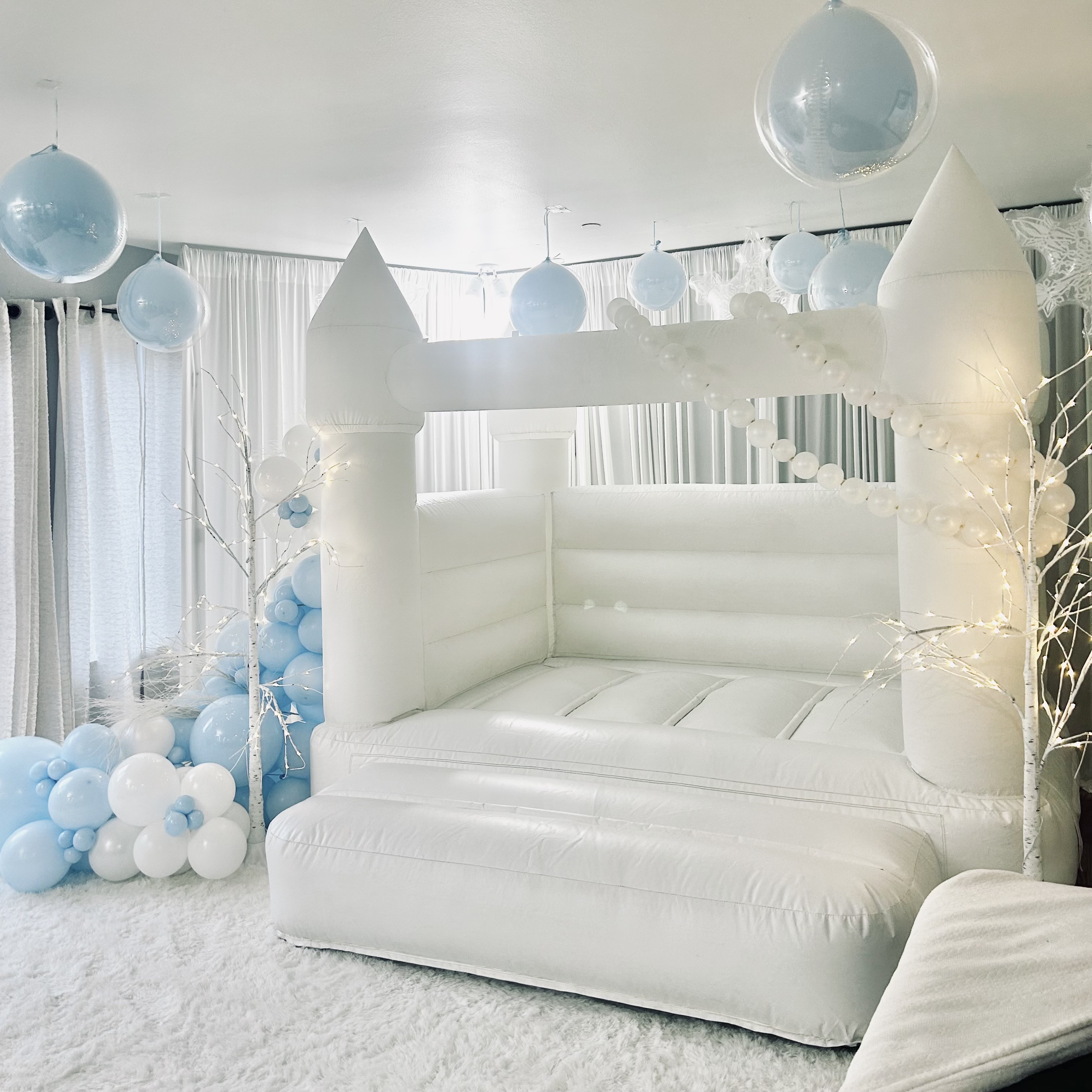 Thaya white bounce house with white and powder blue balloon garland for a first birthday in Lynnwood, WA