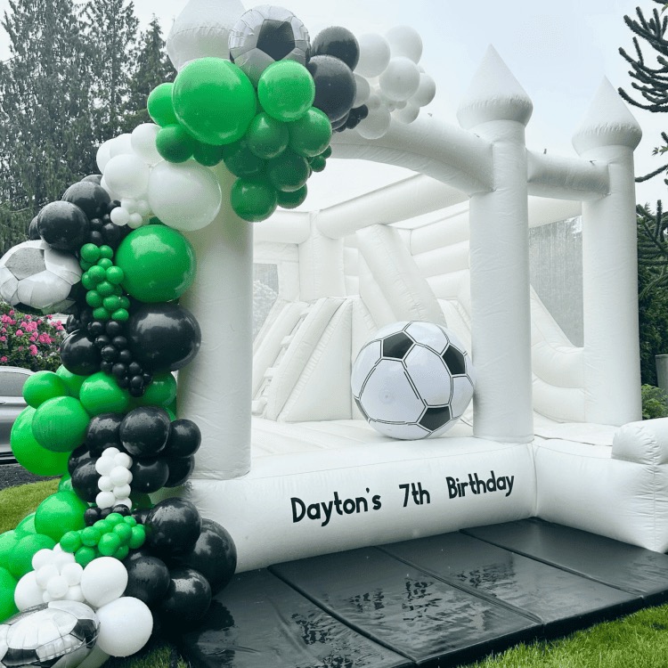 Custom Signage white bounce house with emerald, black, and white balloon garland for a birthday in Monroe, WA