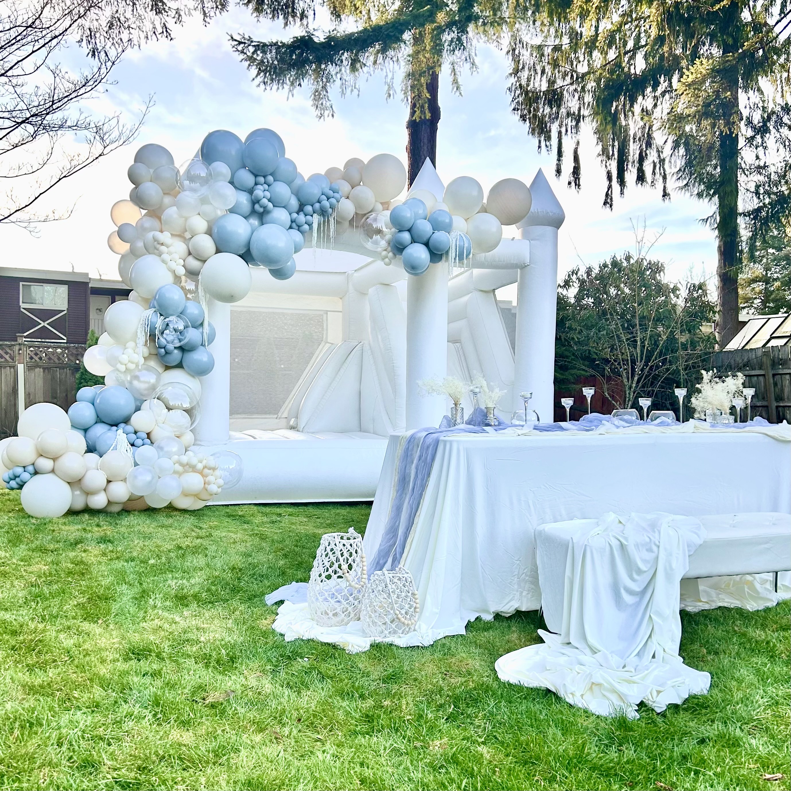 Ranier white bounce house with white, powder blue, and ivory balloon garland for a wedding in Monroe, WA