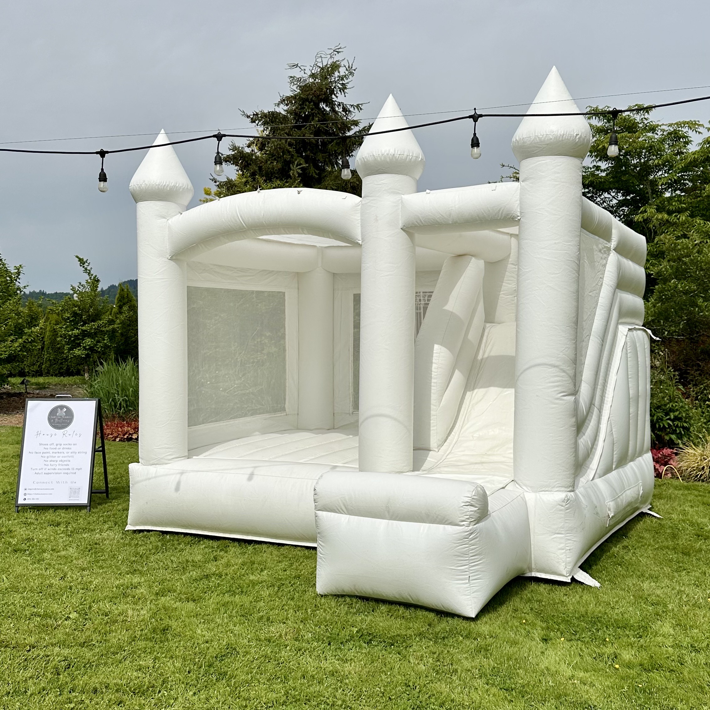 St Helens white bounce house with white balloon garland for a wedding at Falling Water Gardens in Monroe, WA