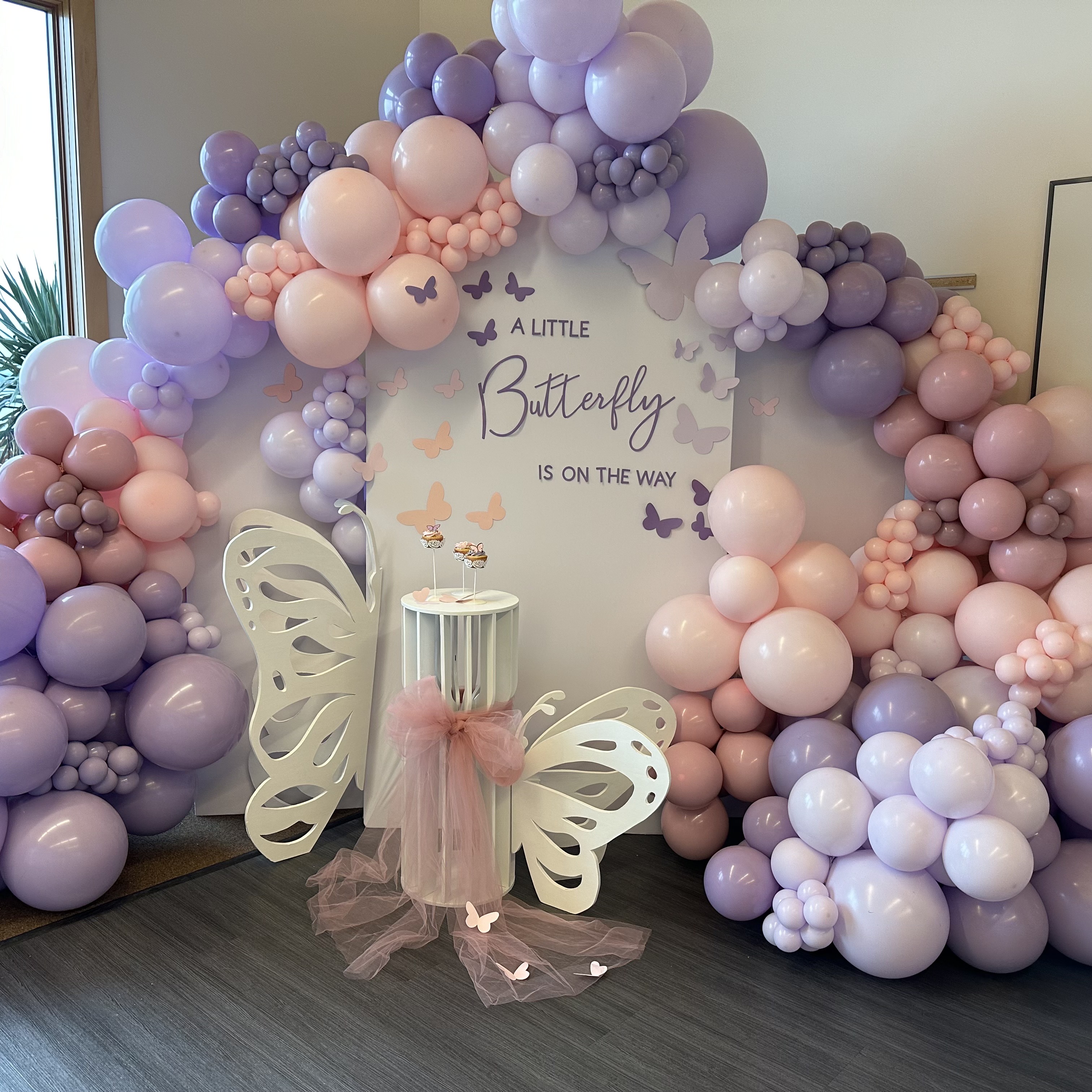 Blush, lavender, and ivory balloon garland and butterfly themed backdrop for a baby shower at Rosehill Community Center in Mukilteo, WA